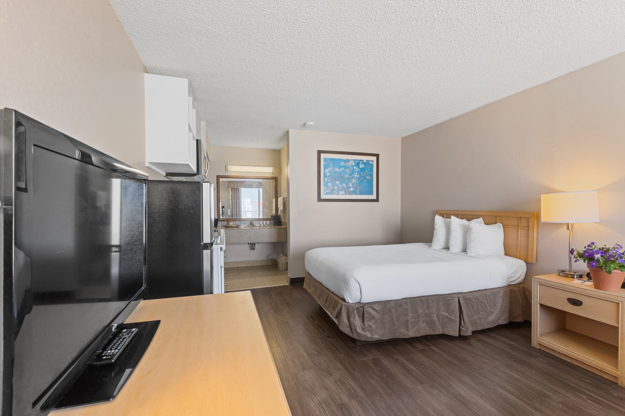 Kitchenette room with fridge, bed and fresh flowers
