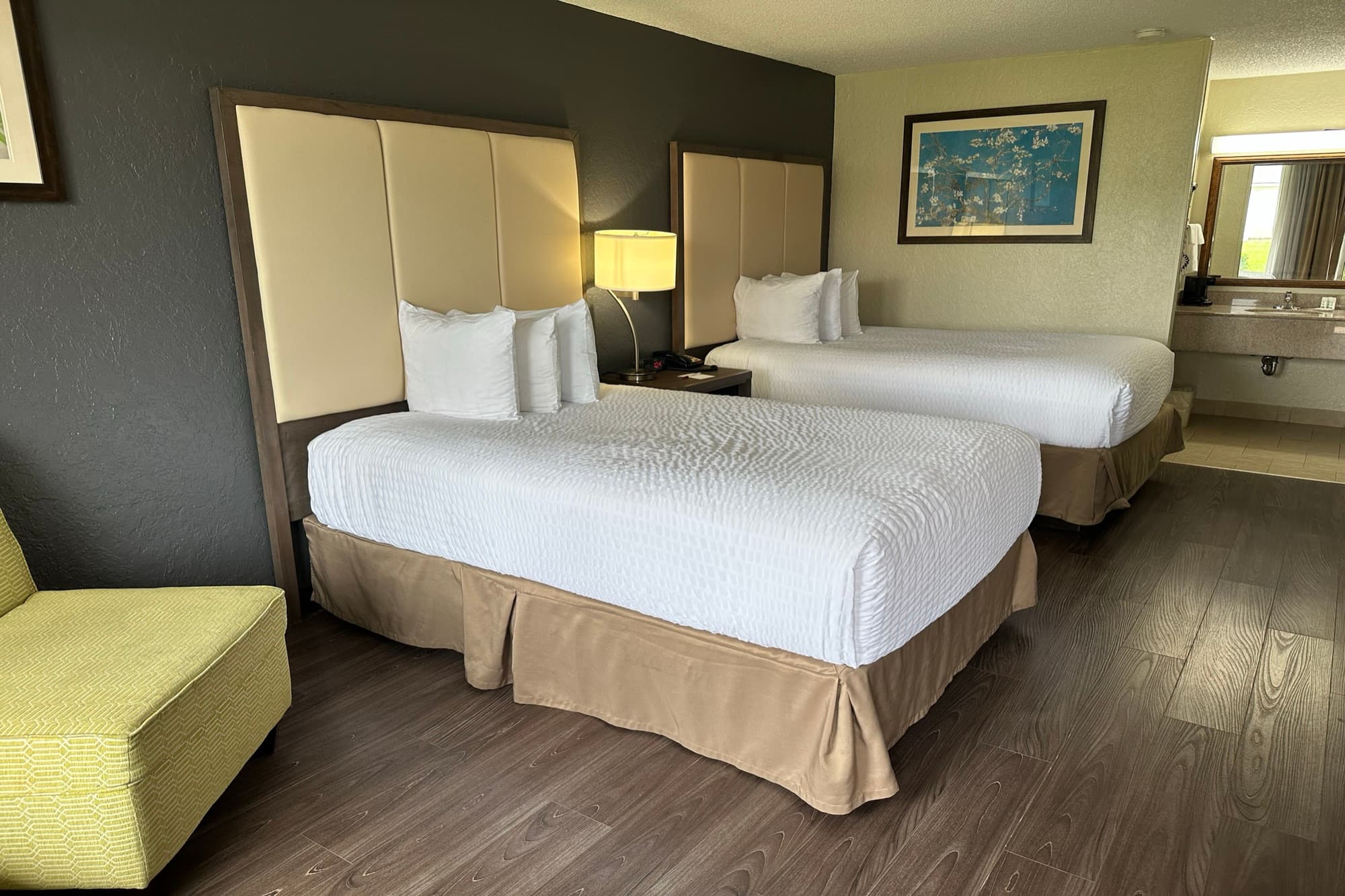 Two queen beds with crisp white linens and a dark feature wall